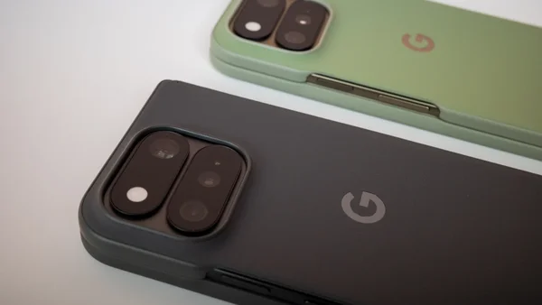 Dos de deux smartphones Google Pixel 11, l'un en étui gris foncé et l'autre en vert clair, mettant en évidence leurs modules caméra distinctifs et le logo Google 'G'.