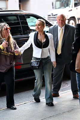 Hayden Panettiere arrivant aux studios CBS Mornings à New York en mai 2026, vêtue d'un blazer blanc McQueen, d'un top en dentelle noire, d'un jean évasé et tenant la main d'une autre femme sur un trottoir.