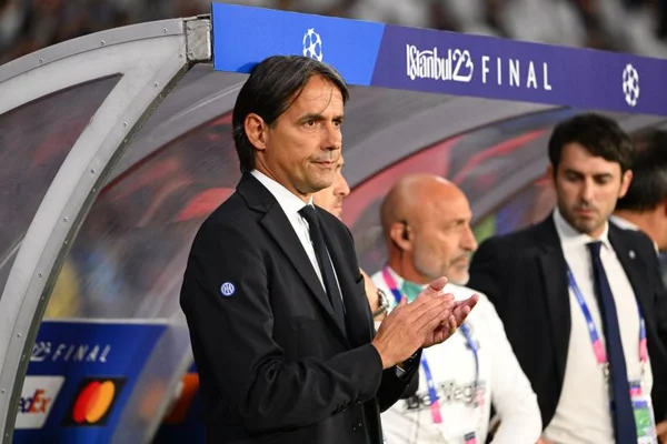 Simone Inzaghi en costume sombre et cravate applaudissant devant un banc de touche avec une bannière « Istanbul 23 FINAL »
