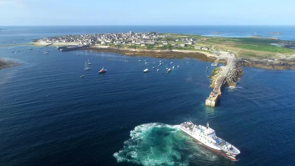 Vue aérienne du port de Molène en Bretagne, avec des bateaux ancrés et un ferry naviguant vers un quai en pierre