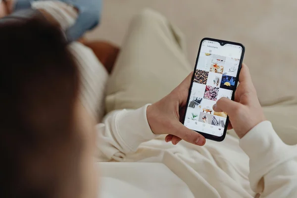 Personne tenant un smartphone et faisant défiler passivement un profil Instagram, illustrant le lien entre la consommation passive de réseaux sociaux et l'anxiété chez les adolescents