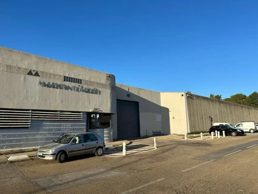 Façade en béton de la maison d'arrêt de Nîmes sous un ciel bleu, illustrant la problématique de la surpopulation carcérale