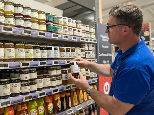 Étiquetage sur l'origine du miel dans le rayon supermarché, illustrant les nouvelles obligations issues de la directive européenne pour les consommateurs.