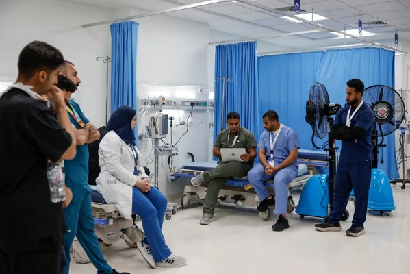 Équipe médicale composée d'un médecin en blouse blanche et de plusieurs hommes en tenues chirurgicales réunis dans une salle d'hôpital lors du pèlerinage du Hajj 2026 à La Mecque.