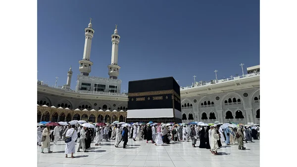 La Kaaba dans la Grande Mosquée de La Mecque sous un ciel bleu dégagé, avec des pèlerins effectuant le tawaf autour du sanctuaire lors du Hajj 2026.