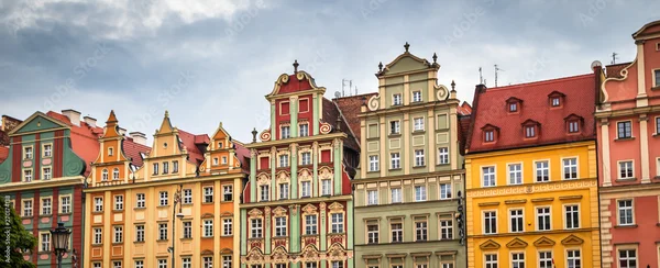 Bâtiments historiques colorés et ornés sur la place du marché (Rynek) dans la vieille ville de Wroclaw, sous un ciel nuageux.