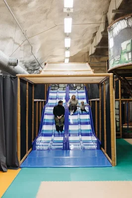 Terrain de jeux d'enfants dans un abri anti-bombes souterrain à Helsinki, illustrant l'utilisation en temps de paix des infrastructures de protection finlandaises.