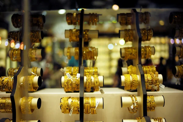 Bracelets en or de divers designs exposés dans une bijouterie, illustrant les contrôles contre le commerce illicite de l'or.
