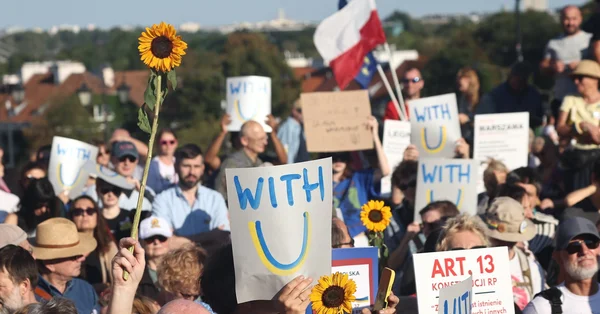 Manifestation de nuit contre les violences anti-ukrainiennes, avec des drapeaux ukrainiens et des pancartes en plusieurs langues tenus par des participants dans une rue de ville polonaise.