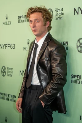 Jeremy Allen White, acteur, lors du 63e festival du film de New York à Lincoln Center en 2025 pour le film Springsteen: Deliver Me from Nowhere, posant sur un tapis vert avec logos NYFF63 et Rolex, vêtu d'une veste en cuir marron, chemise blanche et cravate noire.