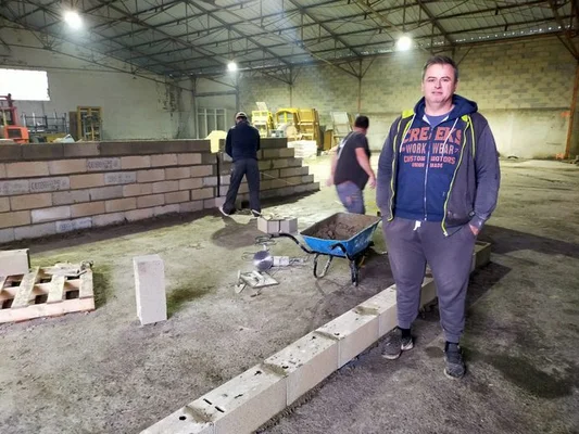 Article de ladepeche.fr sur la construction de l'usine de préservatifs à Condom : homme en sweat à capuche bleu et pantalon gris dans un entrepôt en chantier avec ouvriers.