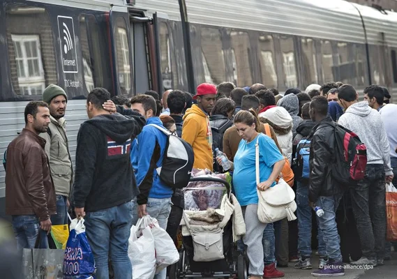 Groupe de personnes, beaucoup portant des bagages et une poussette, sur un quai de gare près d'un train, illustrant l'article d'InfoMigrants sur la dissuasion des étrangers au Danemark.