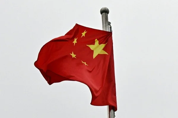 Drapeau national de la République populaire de Chine, champ rouge à cinq étoiles jaunes flottant sur un mât contre un ciel couvert, en lien avec l'interdiction aérienne civile au large de Shanghai.