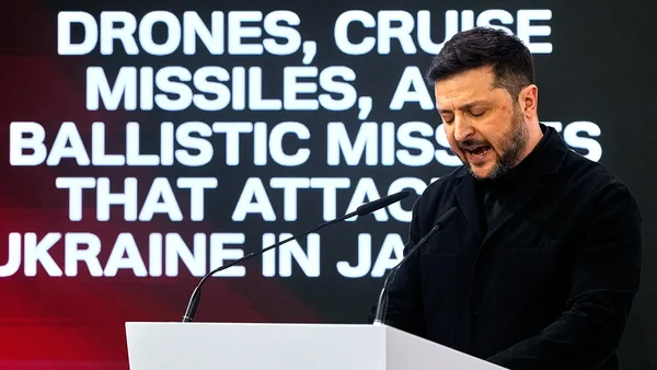 Zelensky, président ukrainien à la barbe et en veste noire, s'exprimant depuis un podium blanc devant des micros, avec un écran évoquant l'absence de l'Europe aux pourparlers de paix et les attaques de missiles.