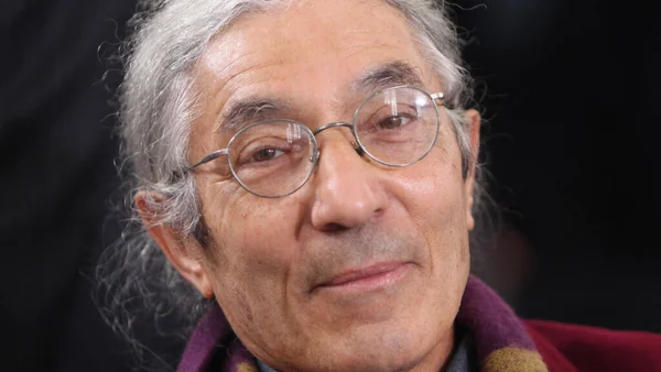 Boualem Sansal, écrivain algérien, lors de la remise du Prix de la paix de la Fédération allemande du livre à Francfort-sur-le-Main le 13 octobre 2013, en gros plan avec cheveux gris, lunettes rondes, veston bordeaux et écharpe violette.