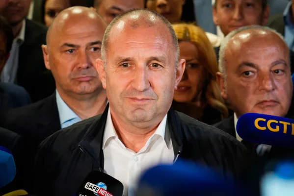 En Bulgarie, Roumen Radev victorieux des législatives, homme d'âge mûr en chemise blanche et veste sombre, parlant à des reporters avec micros lors d'une prise de parole.