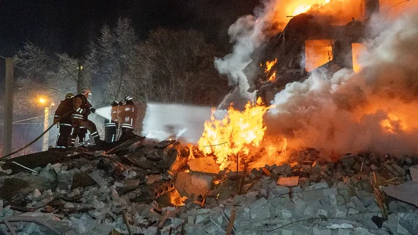 Ukraine : pompiers en tenue complète luttant contre un incendie enveloppant un immeuble de plusieurs étages à Kharkiv la nuit, après des frappes russes ayant fait treize morts.