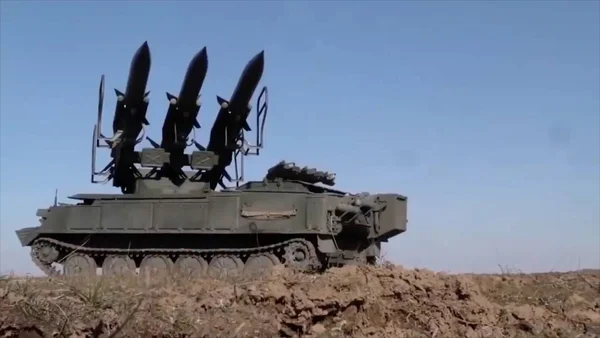 Véhicule militaire à chenilles du système sol-air Bouk transportant trois missiles, positionné sur un monticule de terre sous un ciel bleu, symbole de la défense antiaérienne ukrainienne.