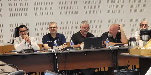 Cinq hommes assis derrière une longue table lors d'une réunion de la Journée FO des ARS 2026 (échanges, vigilance et mobilisation), avec micros, bouteilles d'eau et ordinateur portable.
