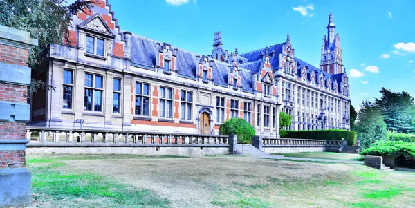 La faculté de droit de l'université libre de Bruxelles, grand bâtiment historique en brique rouge et pierre avec une tour proéminente et une pelouse au premier plan, cadre du campus étudié.