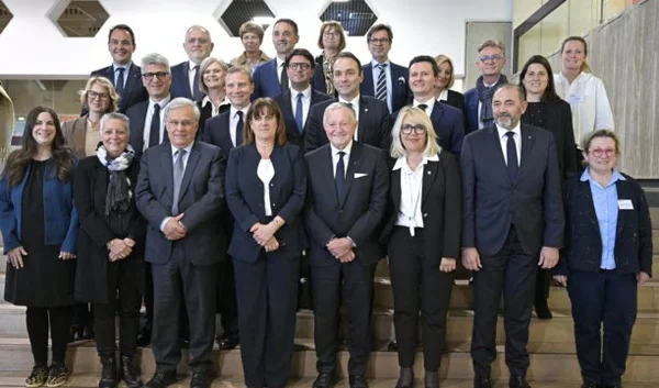 La présidente de la Métropole aux côtés de ses 25 vice-présidents, posant pour une photographie de groupe professionnelle sur un escalier intérieur, vêtus de tenues formelles.