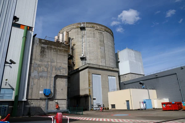 Vue extérieure de la centrale nucléaire de Fessenheim dans le Haut-Rhin, montrant une grande structure cylindrique en béton et des bâtiments adjacents sous un ciel bleu, dans le cadre de son démantèlement.