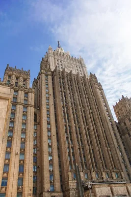 Le bâtiment du ministère de la Santé de la Fédération de Russie, photographié en contre-plongée, montre une façade imposante et étagée de style stalinien avec une tour centrale pointant vers un ciel bleu nuageux.