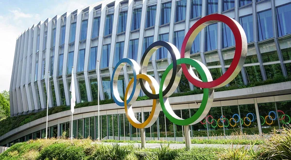 Sculpture colorée des anneaux olympiques devant le siège du CIO, bâtiment de verre courbe à Lausanne, en Suisse.