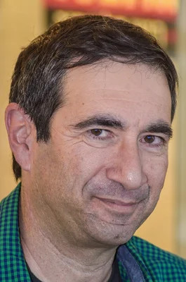 Dov Alfon, directeur de la rédaction de Libération, homme d'âge moyen aux cheveux courts et foncés vêtu d'une chemise à carreaux verts et bleus, souriant légèrement et regardant l'objectif, à l'occasion de l'annonce de son départ après six ans à la tête du quotidien.