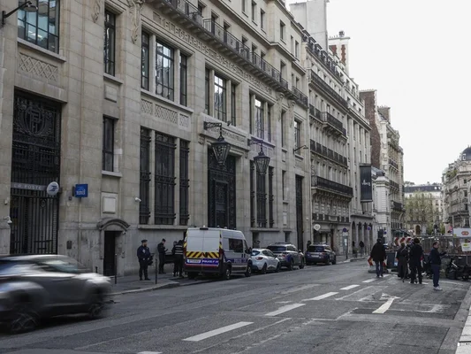 Attentat déjoué à Paris devant les locaux de la Bank of America : vue de rue avec un grand bâtiment en pierre portant l'inscription 'TELEGRAPHES POSTES TELEPHONES', des policiers et un fourgon de police stationnés à l'extérieur.