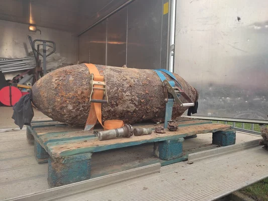 Lors de l'évacuation d'un village alsacien pour neutraliser une bombe de la Seconde Guerre mondiale, un objet cylindrique rouillé ressemblant à un engin non explosé est sanglé orange et bleu sur une palette dans un camion.