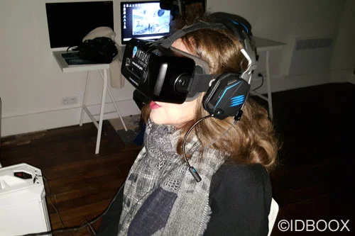 Illustration de théâtre en réalité virtuelle : une femme de profil porte un casque VR et des écouteurs, devant un ordinateur portable et un moniteur en arrière-plan.