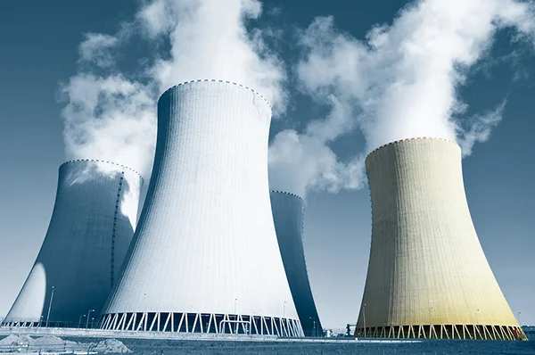 Centrale nucléaire composée de quatre grandes tours de refroidissement émettant de la vapeur blanche sous un ciel bleu dégagé, image d'illustration provenant de TéléAlerte.