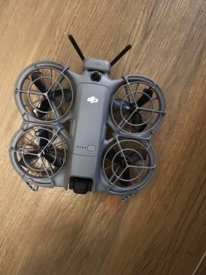 Drone DJI Neo 2 gris vu de dessus, avec quatre hélices encadrées de protections, posé sur une surface en bois.