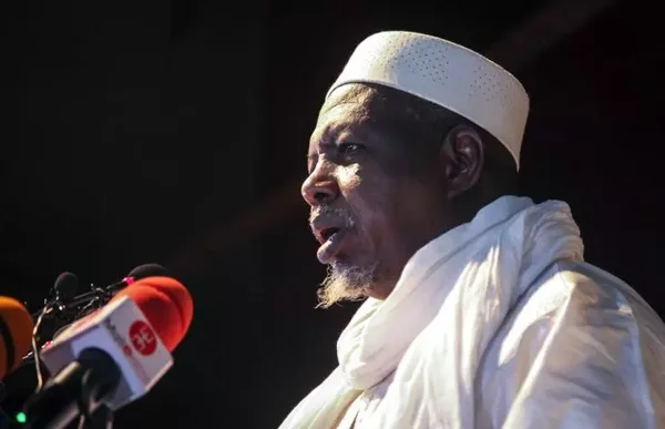 Photographie d'un homme à barbe grise en tenue blanche s'adressant à la presse, évoquant le contexte régional élargi du Mali, de l'Algérie et du Maroc, sans lien direct avec le retour de l'ambassadeur.