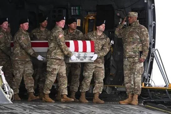 Des soldats de l'armée américaine en uniforme de camouflage et béret noir transportent un cercueil couvert d'un drapeau depuis un avion militaire sur la base aérienne de Muwaffaq Salti en Jordanie, après des frappes de missiles iraniens.
