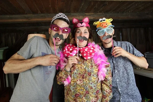 Article sur la soirée déguisée d'Etudiant en France : trois personnes posant à l'intérieur avec accessoires de photobooth, diadème, headbands animaux, lunettes, fausses moustaches et boa rose.