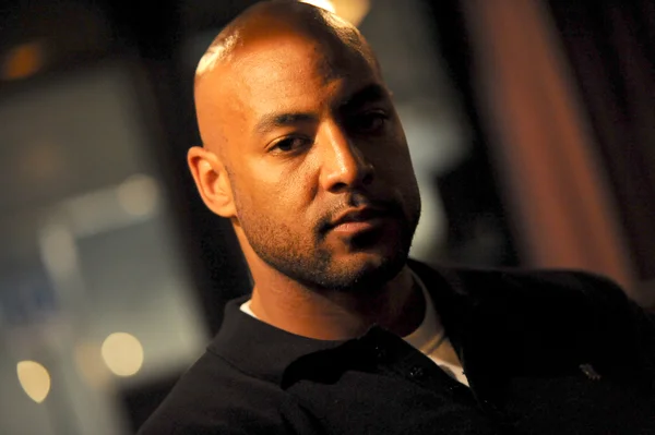 Portrait en gros plan du rappeur Booba (Thonny boom j) daté du 15 août 2003, portant un polo sombre avec une chemise blanche en dessous, avec une expression sérieuse