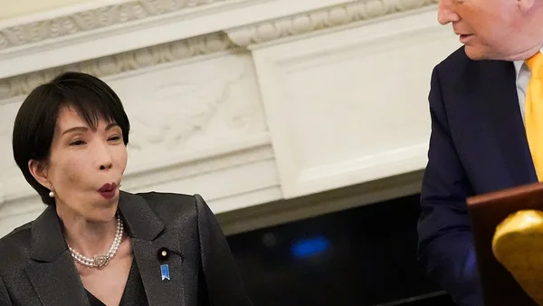 Donald Trump en costume à côté de la première ministre japonaise affichant une moue pincée, lors du moment de gêne créé par la blague de Trump sur Pearl Harbor.