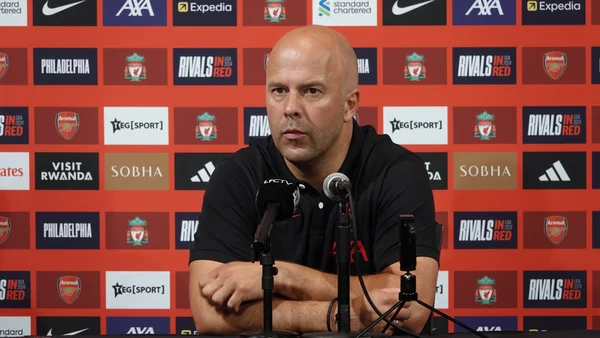 Arne Slot, chauve, en polo noir, à une table de conférence de presse avec micros devant un fond rouge aux logos Liverpool FC à Philadelphie le 31 juillet 2024.