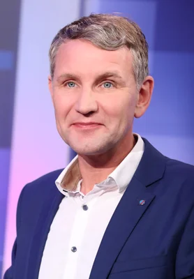 Björn Höcke, figure de l'AfD, en portrait en buste lors de la soirée électorale en Thuringe en 2019, homme d'âge moyen aux cheveux grisonnants et yeux bleus, portant un blazer marine sur chemise blanche.