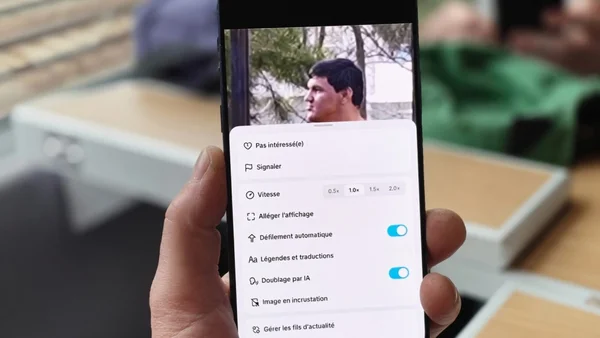 Première vue de la main d'une personne tenant un smartphone affichant le menu de lecture vidéo de TikTok avec des options en français comme 'Vitesse' et 'Défilement automatique', illustrant l'interface de contrôle.