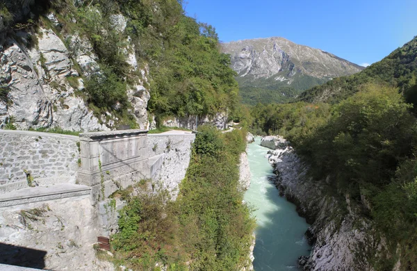 Photographie d'un voyage routier européen en 2011 montrant une rivière turquoise dans un gorge rocheuse en Slovénie, avec une paroi rocheuse et une végétation luxuriante sous un ciel bleu.