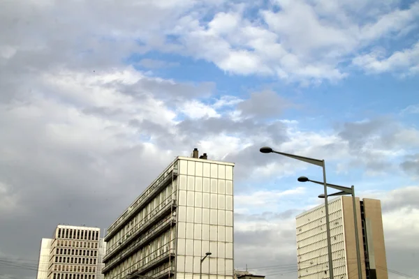 Vue en hauteur des immeubles modernes de l'avenue du 8-Mai-1945 et de la place de France à Sarcelles sous un ciel bleu nuageux.