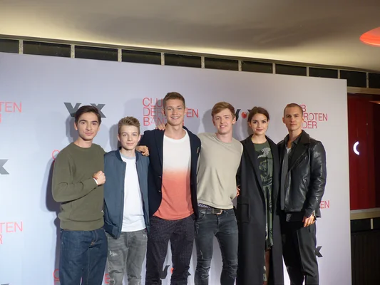 Thomas Brodie-Sangster et Dylan O'Brien posant avec quatre autres comédiens lors de l'événement promotionnel de la saison 2 de "Club der roten Bänder" en octobre 2016, devant une banderole pour "The Maze Runner".