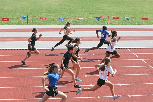 Jeunes athlètes féminines de l'UNSS en plein effort lors de la première journée des championnats de France d'athlétisme à Tomblaine, sur une piste rouge.