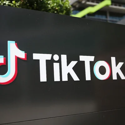 Vue de près d'un panneau physique affichant le logo et le nom de TikTok en texte blanc avec des accents rouge et bleu sur fond noir, représentant l'identité de marque de l'application.