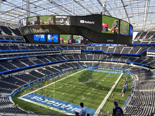 Intérieur du SoFi Stadium lors d'un match des Los Angeles Chargers contre les Minnesota Vikings, avec un écran vidéo double suspendu au-dessus du terrain.