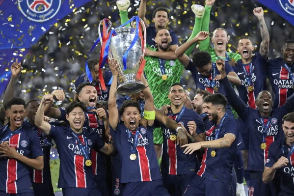 Joueurs du Paris Saint-Germain en maillots bleu et rouge célébrant sur la pelouse en soulevant le trophée argenté de la Ligue des champions orné de rubans, sous une pluie de confettis après la victoire 5-0 contre l'Inter Milan en finale