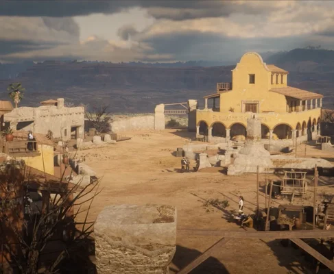 Capture du mod massif Nuevo Paraíso pour Red Dead Redemption 2 recréant le Mexique de RDR1, montrant une place de village poussiéreuse avec un bâtiment jaune à arcades portant l'enseigne El Aljarde de la Huerca et plusieurs personnages en tenue d'époque